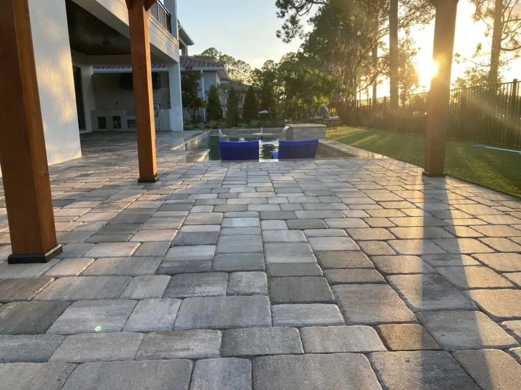 Sealed paver pool deck with a pergola at sunset