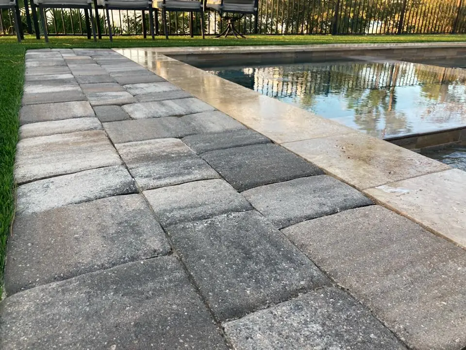 Sealed paver pool deck with travertine coping at the water's edge