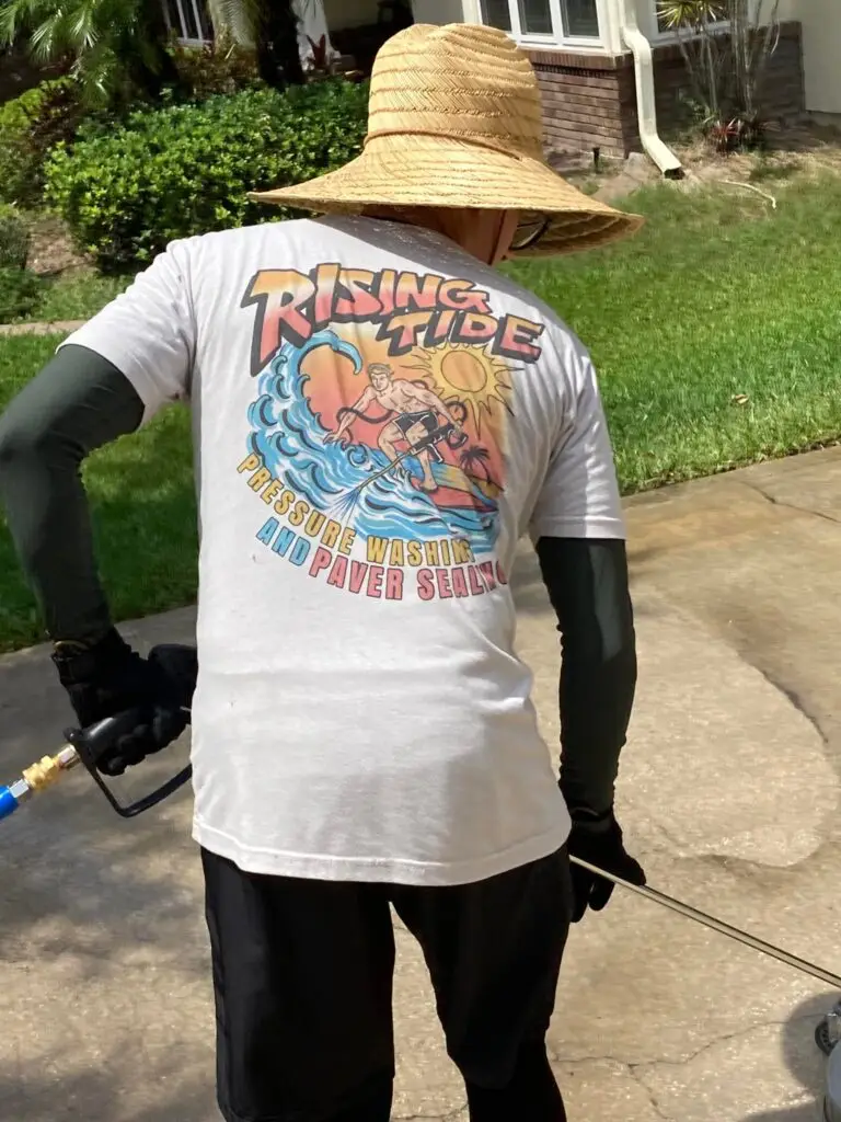Rising Tide Paver Sealing technician with a pressure washing wand on a job site